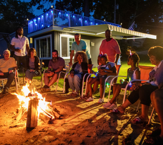 Awning with LED Lights on behind large group of people enjoying a campfire