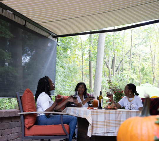 family carving pumpkins underneath an awning