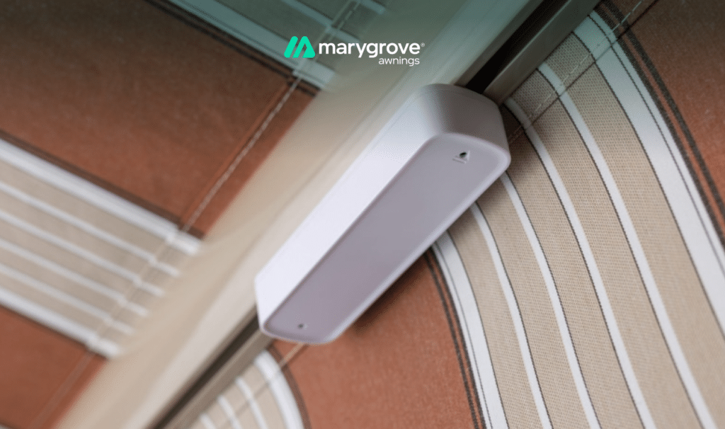 Close-up of a white wind sensor attached to a Marygrove retractable awning with striped fabric.