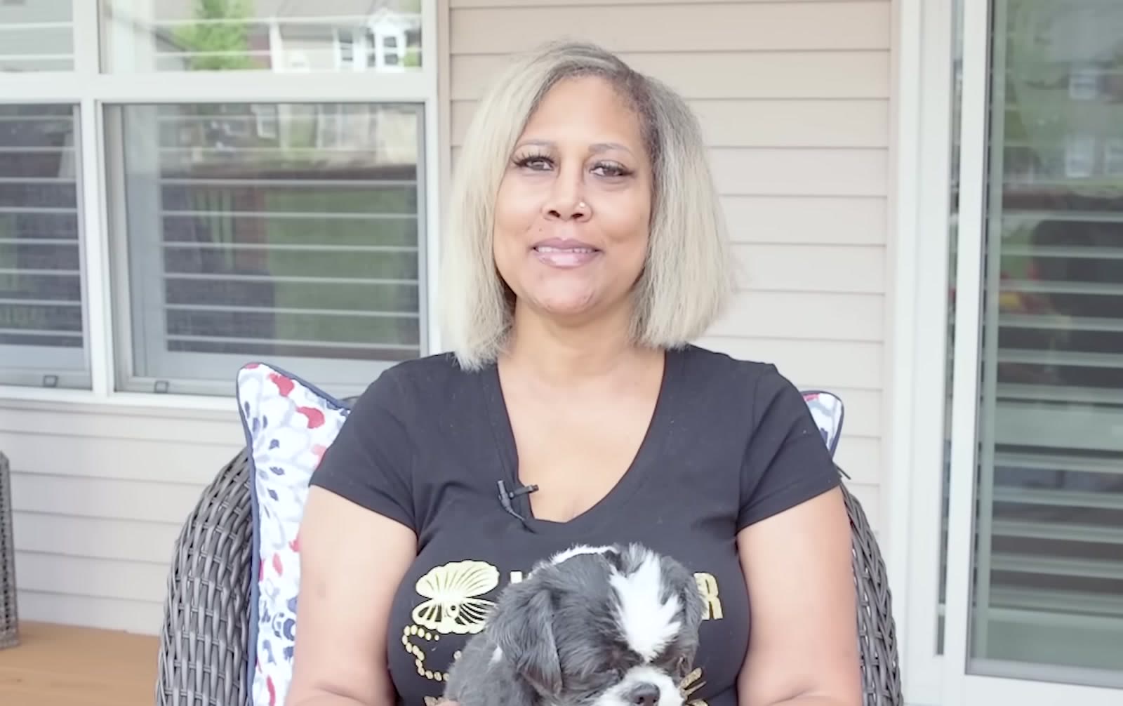 Customer seated on her patio holding a small dog