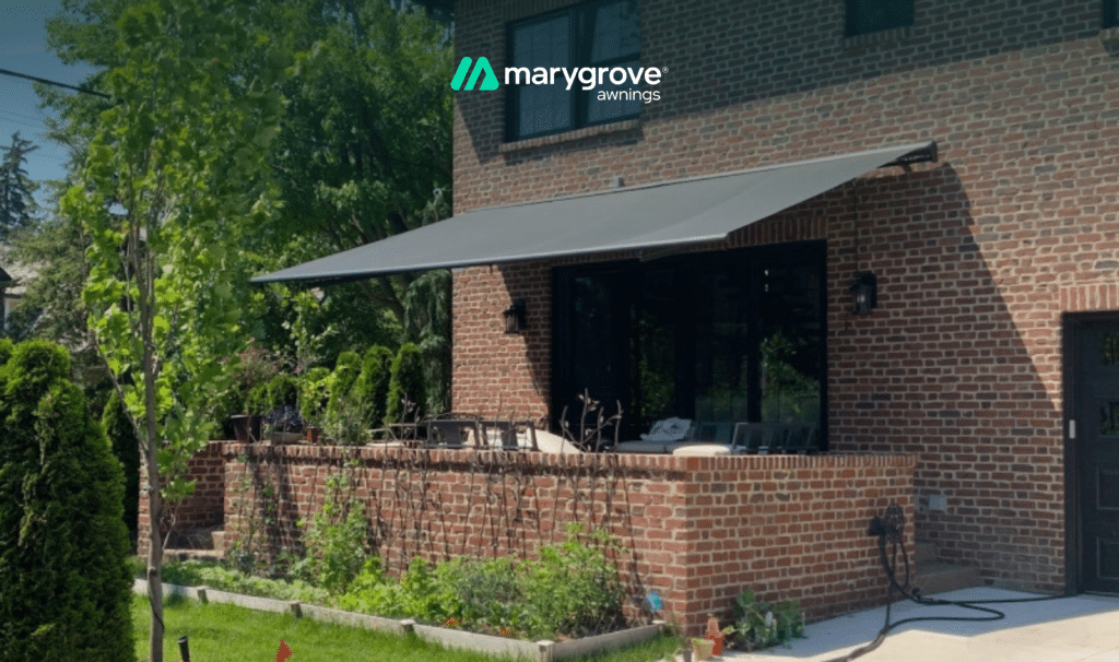 Marygrove retractable awning extended over an enclosed brick patio on a brick home.