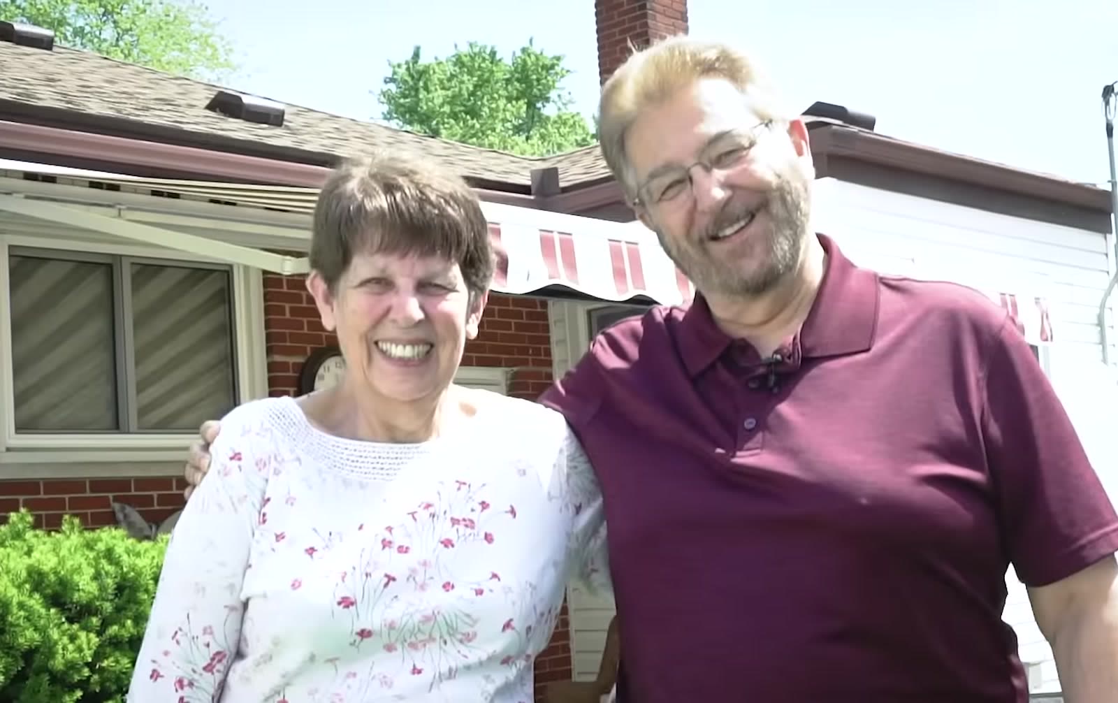 Couple standing in front of their home with a retractable awning